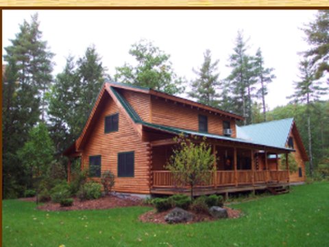 Custom log home with a covered wraparound porch, built by Wellington Log Homes