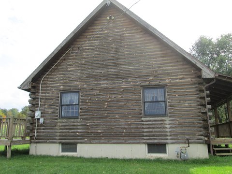 Weathered log home gable wall before restoration